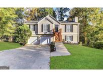 Charming home featuring a two-car garage, inviting front porch, manicured lawn, and surrounded by mature trees at 6220 Grovener Ave, Douglasville, GA 30134