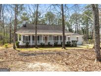Charming one-story home with a welcoming porch, surrounded by trees, and well-maintained landscaping at 195 Willow Way, Stockbridge, GA 30281