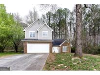 Charming two-story home featuring a brick and gray siding exterior and a two-car garage in a wooded neighborhood at 3821 Rex Mill Sq, Rex, GA 30273