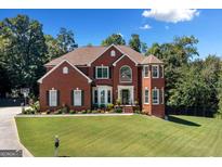 Stunning two-story brick home boasts lush landscaping and a well-manicured lawn under a bright, partly cloudy sky at 3015 Gold Creek Dr, Villa Rica, GA 30180