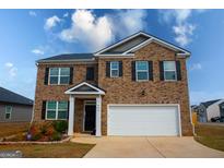 Two-story brick home featuring a two-car garage, black shutters, and a well-maintained front yard at 443 Faulkner St, Stockbridge, GA 30281