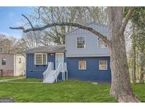 Charming two-story home featuring a blue exterior, brick foundation, and a well-maintained green lawn at 6192 Holiday Blvd, Forest Park, GA 30297