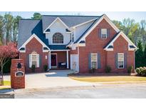 Charming two-story brick home featuring a dark roof, inviting front porch and well-manicured lawn and landscaping at 106 Victoria Way, Carrollton, GA 30116