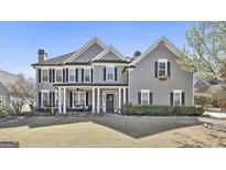 Beautiful two-story home featuring a covered porch with black shutters, and lush landscaping at 160 Stanley Oaks Pl, Fayetteville, GA 30214