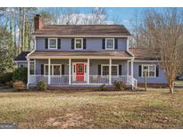 Charming two-story home features a welcoming front porch, blue siding, black shutters, and a striking red front door at 130 Thornton Dr, Fayetteville, GA 30214