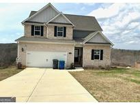 Charming two-story home featuring a two-car garage, stone accents, and a well-manicured lawn at 413 Samara Ct, Fairburn, GA 30213