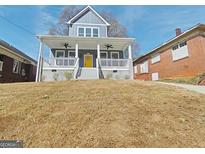 Charming two-story home with a welcoming front porch and bright yellow door at 721 Cascade Sw Ave, Atlanta, GA 30310