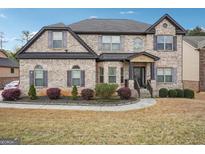 Two-story brick home features a well-manicured lawn and a welcoming front porch with decorative columns at 3863 Rosebay Way, Conyers, GA 30094