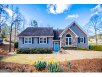 Charming home with stone accents, gray siding, a blue door, and a well-manicured lawn at 2304 Larchmont Ct, Villa Rica, GA 30180