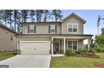 Two-story home featuring a covered front porch, attached two-car garage, and beautifully landscaped yard at 734 Lanarck Way, Peachtree City, GA 30269