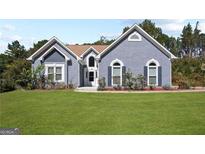 Charming blue stucco home featuring a lush green lawn and well-maintained landscaping at 131 Pecan Lake Dr, Sharpsburg, GA 30277
