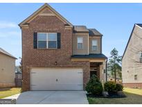 Charming two-story home featuring a brick facade and attached two-car garage, complemented by a well-manicured front yard at 1064 Lear Dr, Locust Grove, GA 30248