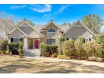 Charming home featuring a stone facade, arched windows, well-maintained landscaping, and a vibrant red front door at 406 Tapley Rd, Villa Rica, GA 30180