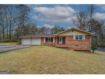 Charming brick home featuring an attached two-car garage and an expansive front yard at 9138 Parnell Sw St, Covington, GA 30014