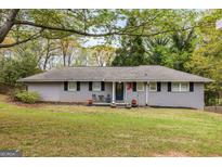 Charming single-story home featuring gray brick, manicured lawn, and inviting front porch at 2341 Elmwood Se Cir, Atlanta, GA 30339