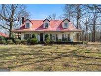 Charming two-story home featuring a red metal roof, dormer windows, and a spacious front yard at 680 Milligan Creek Rd, Roopville, GA 30170