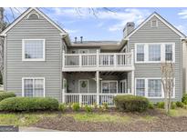 Charming condo featuring double balconies with gray wood siding, white trim, and neatly manicured bushes in the front at 402 Mill Pond Rd # 402, Roswell, GA 30076