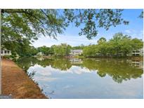 Scenic lake view with mature trees and reflections of community houses enhancing natural beauty at 402 Mill Pond Rd # 402, Roswell, GA 30076