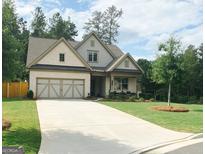 Beautifully landscaped front yard with a charming, light-colored brick and siding two-story home and attached two-car garage at 5745 Pickens Garden Ln, Powder Springs, GA 30127