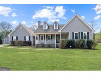 Charming home featuring a well-manicured lawn and inviting front porch with black shutters and a detached garage at 280 Nutt Dr, Locust Grove, GA 30248
