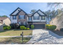 Charming two-story home featuring a stone facade, dark shutters, and a well-manicured front lawn at 8030 Snapwell Dr, Fairburn, GA 30213