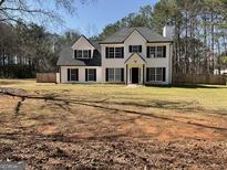 Charming two-story home with black shutters, white paint, black roof and a well-manicured lawn at 1126 Old Jackson Rd, Locust Grove, GA 30248
