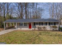 Charming single-story home with a brick facade, red door and a convenient carport at 3465 Tulip Dr, Decatur, GA 30032