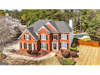 Stunning two-story red brick home with a well-manicured lawn and inviting swimming pool at 265 Ridgewood Dr, Fayetteville, GA 30215