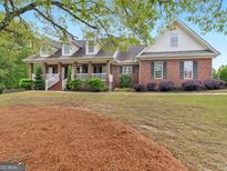 Charming brick home featuring a covered front porch and well-manicured lawn and landscaping at 142 Gillson Dr, Mcdonough, GA 30253