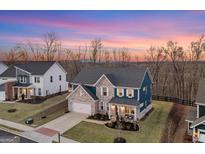 Beautiful two-story home with a brick facade and a manicured lawn on a wooded lot at sunset at 8110 Brewton Bnd, Cumming, GA 30028