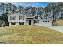 Charming split-level home featuring a fresh white exterior, rustic shutters, and attached two-car garage at 5155 Rosestone Nw Dr, Lilburn, GA 30047