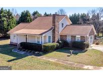 Charming two-story home with brick chimney, manicured lawn, and mature trees at 105 Overlook Dr, Mcdonough, GA 30252