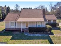 Inviting single-story home featuring a classic brick chimney, well-maintained landscaping, and a charming covered front porch at 105 Overlook Dr, Mcdonough, GA 30252