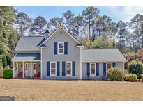 Charming two-story home with blue shutters and a welcoming front porch with red chairs at 107 Bowfin Bay, Peachtree City, GA 30269