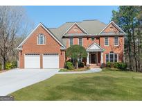 Beautiful two-story red brick home with a manicured lawn, large driveway and attached two car garage at 140 Longwater Cv, Roswell, GA 30075