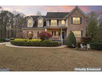 Charming two-story brick home with manicured landscaping and a cozy front porch at 308 Tussahaw Trl, Locust Grove, GA 30248