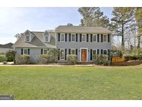 Traditional two-story home featuring a well-manicured lawn and mature landscaping around the facade at 233 Creekstone Bnd, Peachtree City, GA 30269