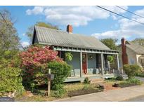 Charming home featuring a metal roof, inviting front porch, and vibrant landscaping with colorful azaleas at 1009 Institute Nw St, Conyers, GA 30012