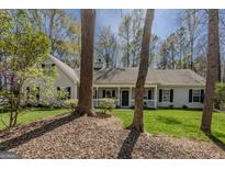 Charming single Gathering home with welcoming front porch and lush landscaping on a sunny day at 65 Dundee Pl, Sharpsburg, GA 30277