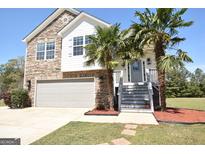 Charming two-story home featuring stone accents, a front-facing garage, and lovely palm trees flanking the entrance at 116 Ducati Dr, Mcdonough, GA 30252