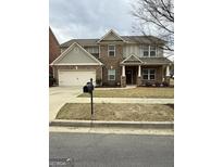 Charming brick and siding two-story home with an attached two-car garage and well-manicured lawn at 2470 Wevok Way, Grayson, GA 30017