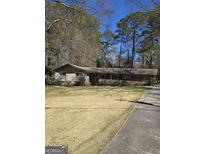 Charming single story home with brick facade, well-maintained lawn, and mature trees on a sunny day at 2527 Amalfi Dr, Conyers, GA 30012