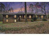 Charming home featuring a metal roof and warm lighting in a wooded setting at 4230 Iris Brooke Ln, Snellville, GA 30039