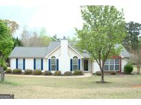Charming one-story home with blue shutters and well-manicured lawn at 329 Harris Ave, Locust Grove, GA 30248