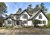 Stately home showcasing white stucco, dark trim, bay windows, and a meticulously landscaped yard with mature trees at 3320 Lost Valley Dr, Jonesboro, GA 30236