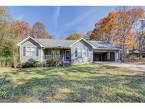 Charming single-story home with a cozy front porch and a convenient carport, surrounded by colorful autumn foliage at 106 Kirkland Rd, Covington, GA 30016
