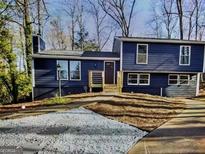 Split level home with blue siding, black door, landscaping, and a concrete driveway with a decorative stone accent at 851 Bridgewater Ct, Stone Mountain, GA 30088