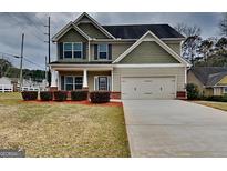 Charming two-story home with green siding, a two car garage, and well manicured landscaping at 483 Castle Top Ln, Lawrenceville, GA 30045