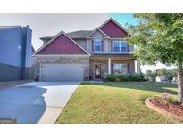 Charming two-story home featuring a brick and siding facade, attached garage, and landscaped front yard at 1058 Hartwell Rd, Locust Grove, GA 30248