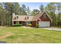 Charming one-story brick home features a manicured lawn and attached two-car garage at 1022 Miss Amber Way, Locust Grove, GA 30248